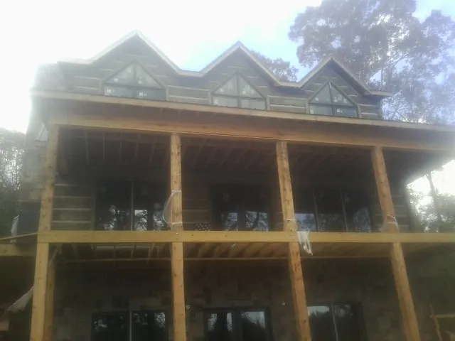 Dormers and porch framing on a large log home under construction — Roof Coating work by our crew in Jones